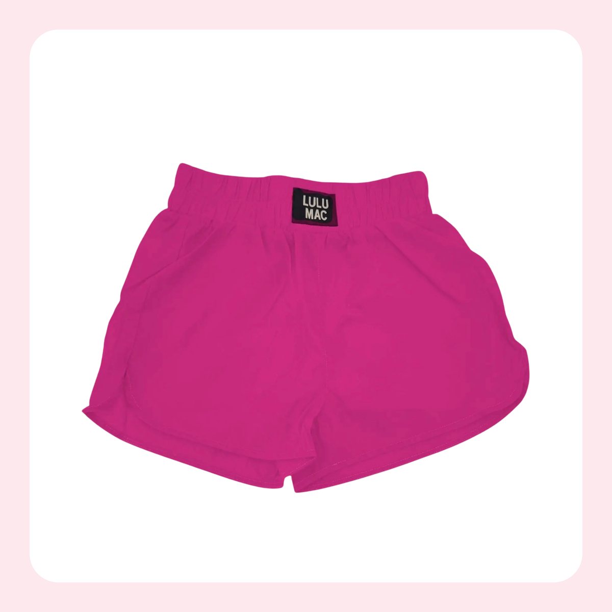 Bright pink athletic shorts with an elastic waistband and a small black brand patch reading 'LULU MAC' on the front, shown on a white background with a soft pink border.