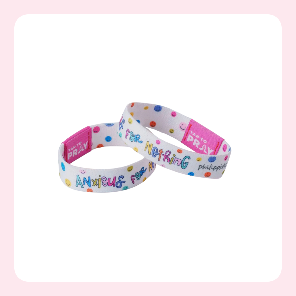 Two white wristbands with colorful polka dots and the words 'Pray For Nothing' and 'Anxious For Peace' printed on them, with pink plastic tags, shown on a white background with a light pink border.