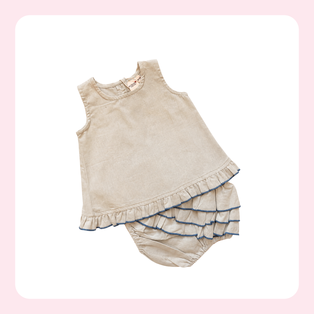 A two-piece baby outfit set in a light beige corduroy fabric, featuring a sleeveless top with a ruffled hem and matching ruffled bloomers with blue piping trim, displayed on a white background with a pink border.