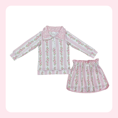 A two-piece girls' pajama set featuring a long-sleeve top and matching skirt in a pink and white striped pattern with vertical pink floral vines and green leaves, displayed on a white background with a light pink border.