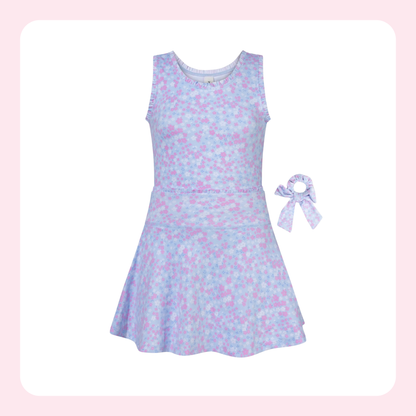A sleeveless girls' dress in a pastel blue and pink floral print, shown with a matching fabric hair bow accessory on a white background with a light pink border.