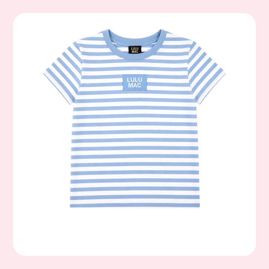A children's short-sleeve crewneck T-shirt with light blue and white horizontal stripes, featuring a light blue chest patch with the text 'LULU MAC' in white, displayed on a clean white background with a soft pink border.