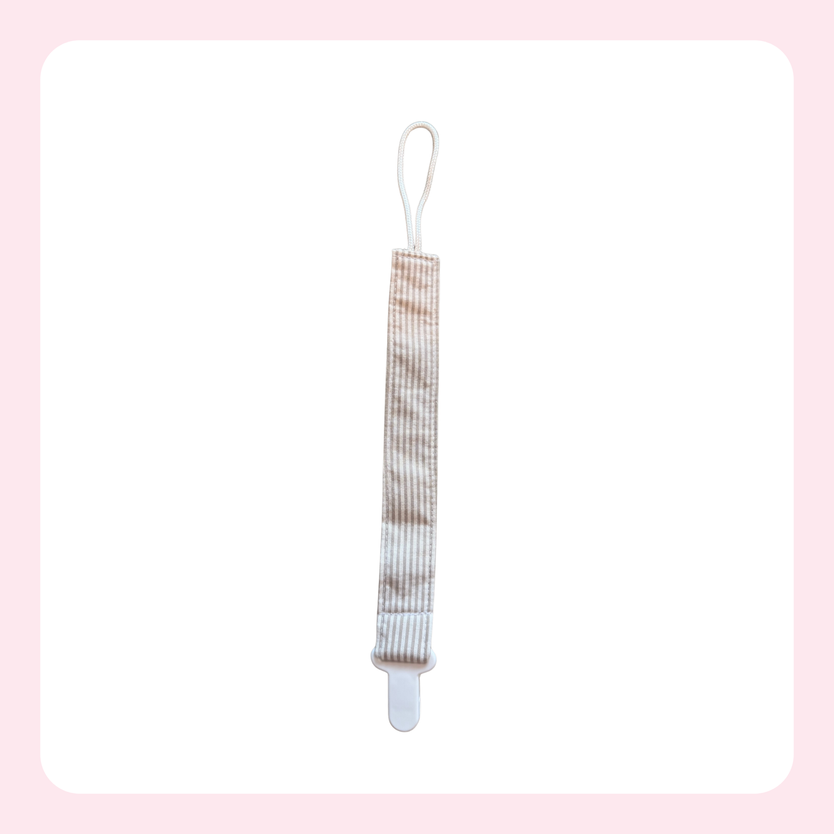 A baby pacifier clip with a beige and white striped fabric strap, white plastic clip, and white loop at the top, shown on a white background with a light pink border.