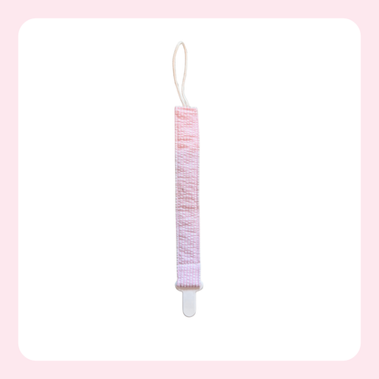 A pink and white patterned fabric hair tie or hair accessory with a white plastic clip and a white loop string, shown against a white background with a light pink border.