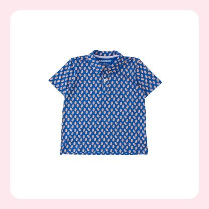 A short-sleeve polo shirt for toddlers, featuring a vibrant blue base with a repeating beige and white paisley pattern. The shirt has a small tie detail at the collar and a short button placket.