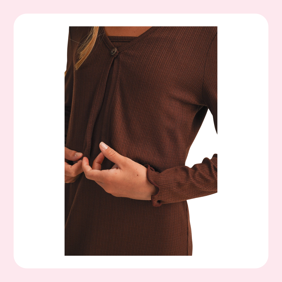 A close-up of a person wearing a dark brown ribbed long-sleeve top with a buttoned neckline and matching cuff buttons, shown against a light pink and white rounded background.