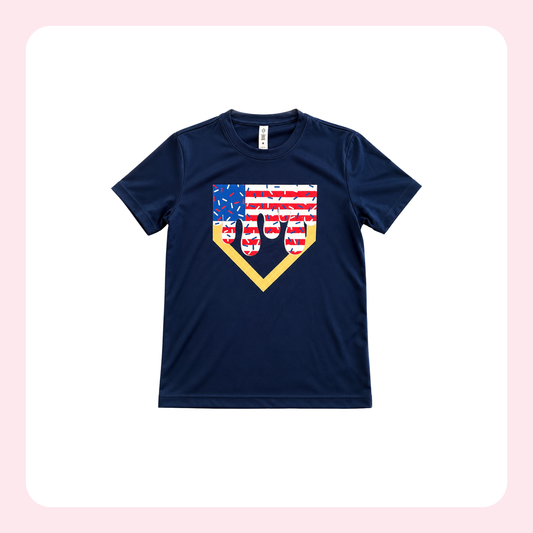 A navy blue short-sleeve t-shirt with a baseball-themed graphic on the chest. The graphic features a home plate outline filled with an American flag pattern (red and white stripes and a blue field with white stars) and a black silhouette of a baseball player in a batting stance.