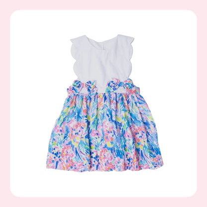 A toddler girl's sleeveless dress with a solid white ruffled yoke and a colorful floral watercolor skirt in shades of blue, pink, purple, and green, displayed on a white background with a soft pink border.