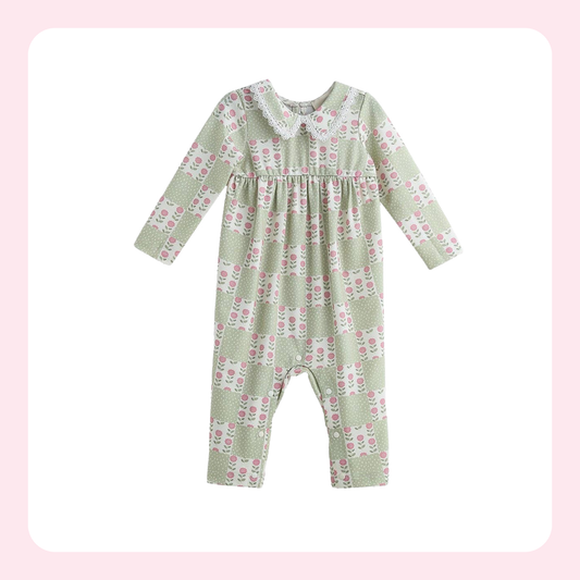 A baby long-sleeve romper in sage green with a pink and white floral pattern, featuring a Peter Pan collar and a smocked chest detail, shown on a white background with a soft pink border.