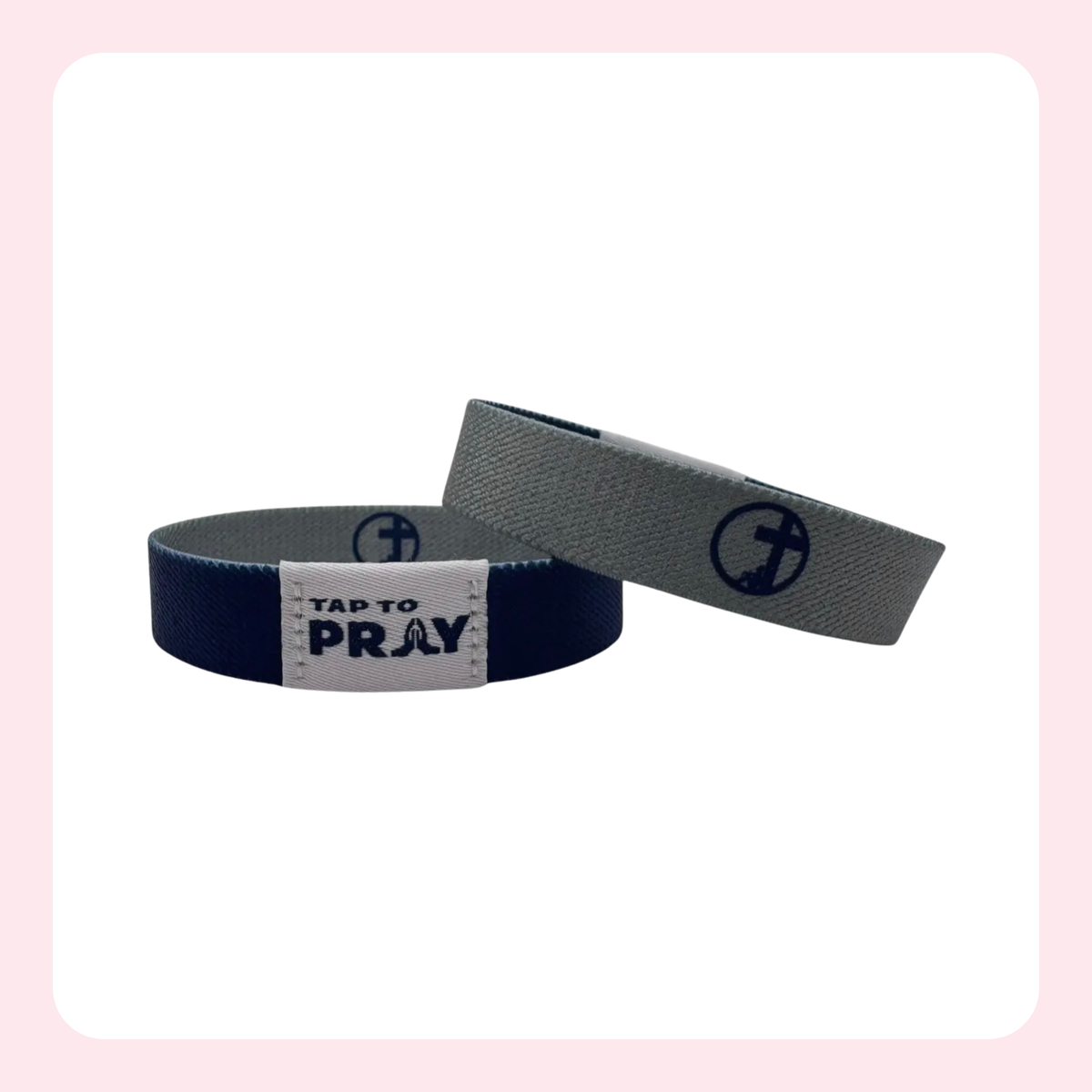 Two wristbands shown on a white background with a light pink border. One wristband is navy blue with a white label that reads 'TAP TO PRAY', and the other is gray with a navy anchor logo.