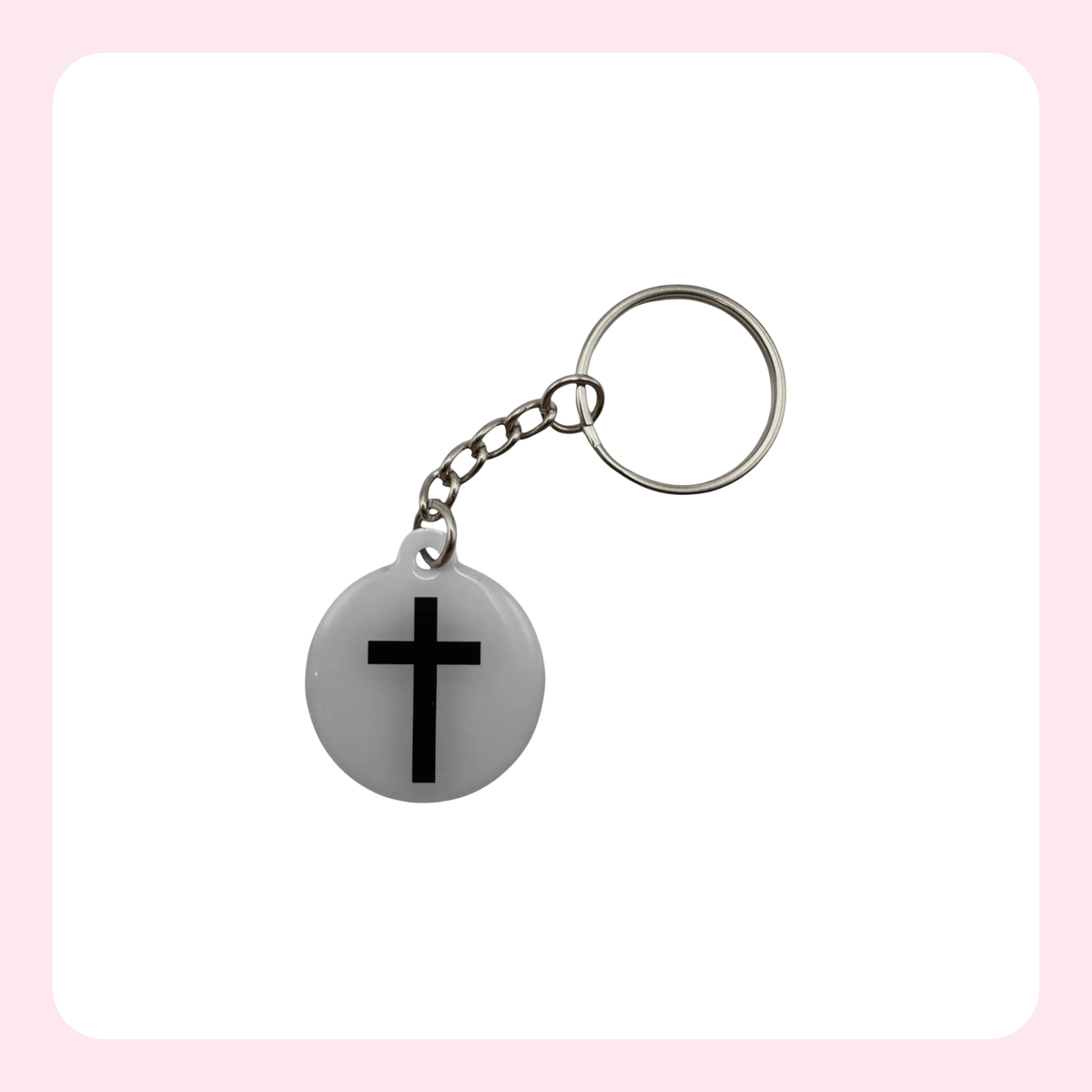 A silver metal keychain with a round white pendant featuring a black cross, set against a white background with a light pink border.