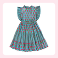 A sleeveless tiered dress with ruffled cap sleeves, featuring a turquoise blue base with a pink floral pattern and small yellow accents, displayed on a white background with a soft pink border.