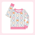 A two-piece children's pajama set featuring a long-sleeve top with a light blue and pink floral pattern and orange pumpkin motifs, paired with solid pink pants.