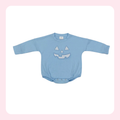 A baby long-sleeve bodysuit in light blue, featuring a sequined jack-o'-lantern face on the chest, displayed flat against a white background with a soft pink border.