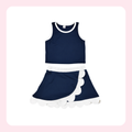 A two-piece girls' outfit set consisting of a navy blue sleeveless crop top with white trim and a matching navy blue skirt with a white ruffle and scalloped edge, displayed on a white background with a light pink border.