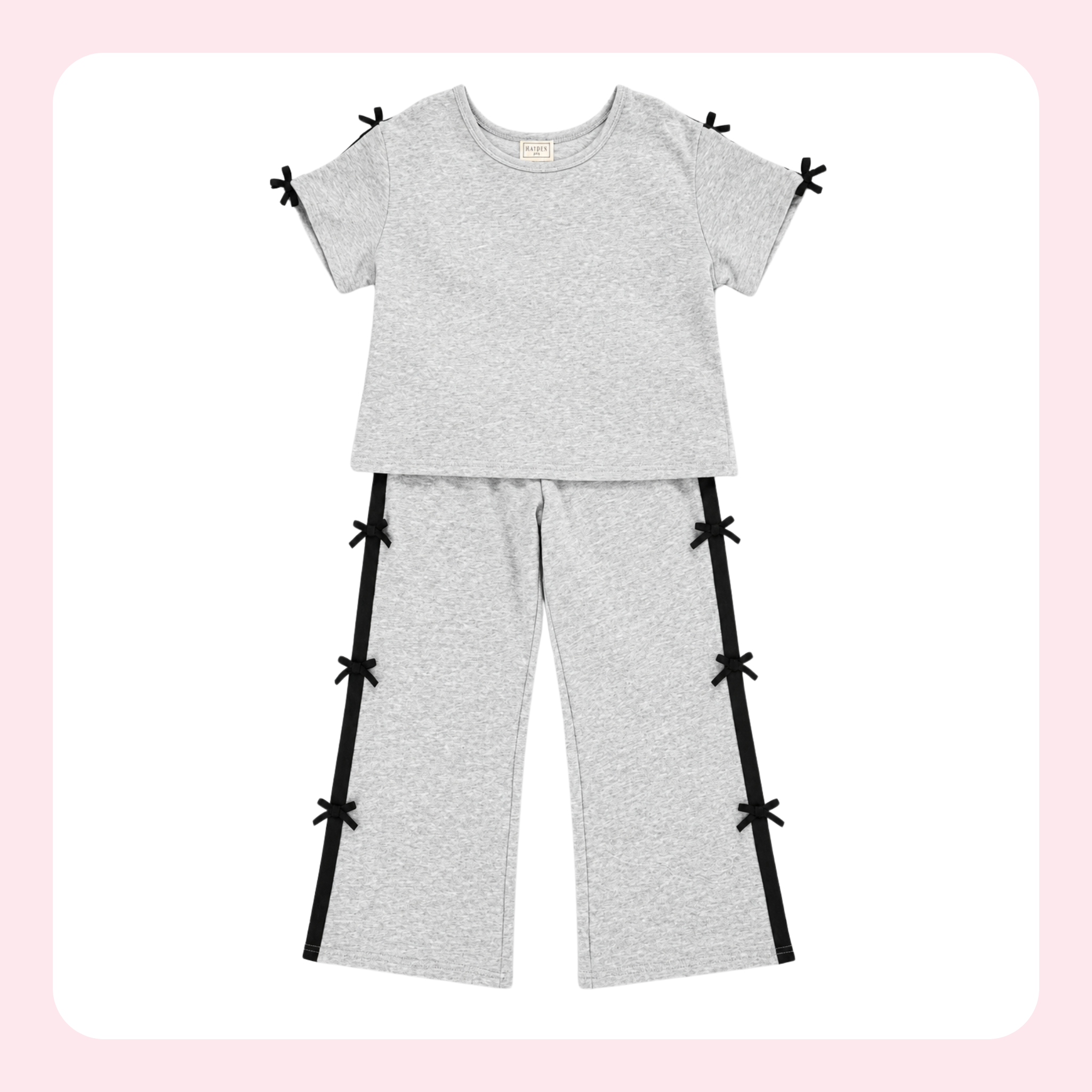 A two-piece kids' loungewear set in light heather gray, featuring a short-sleeve crewneck top and matching wide-leg pants. The set is accented with black side stripes on the pants and small black ribbon bows at the shoulder, sleeve, and pant leg edges.