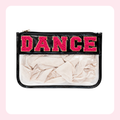A rectangular zippered pouch with a black faux-leather border and a clear front panel. The top band is black with the word "DANCE" in large pink letters outlined in gold.