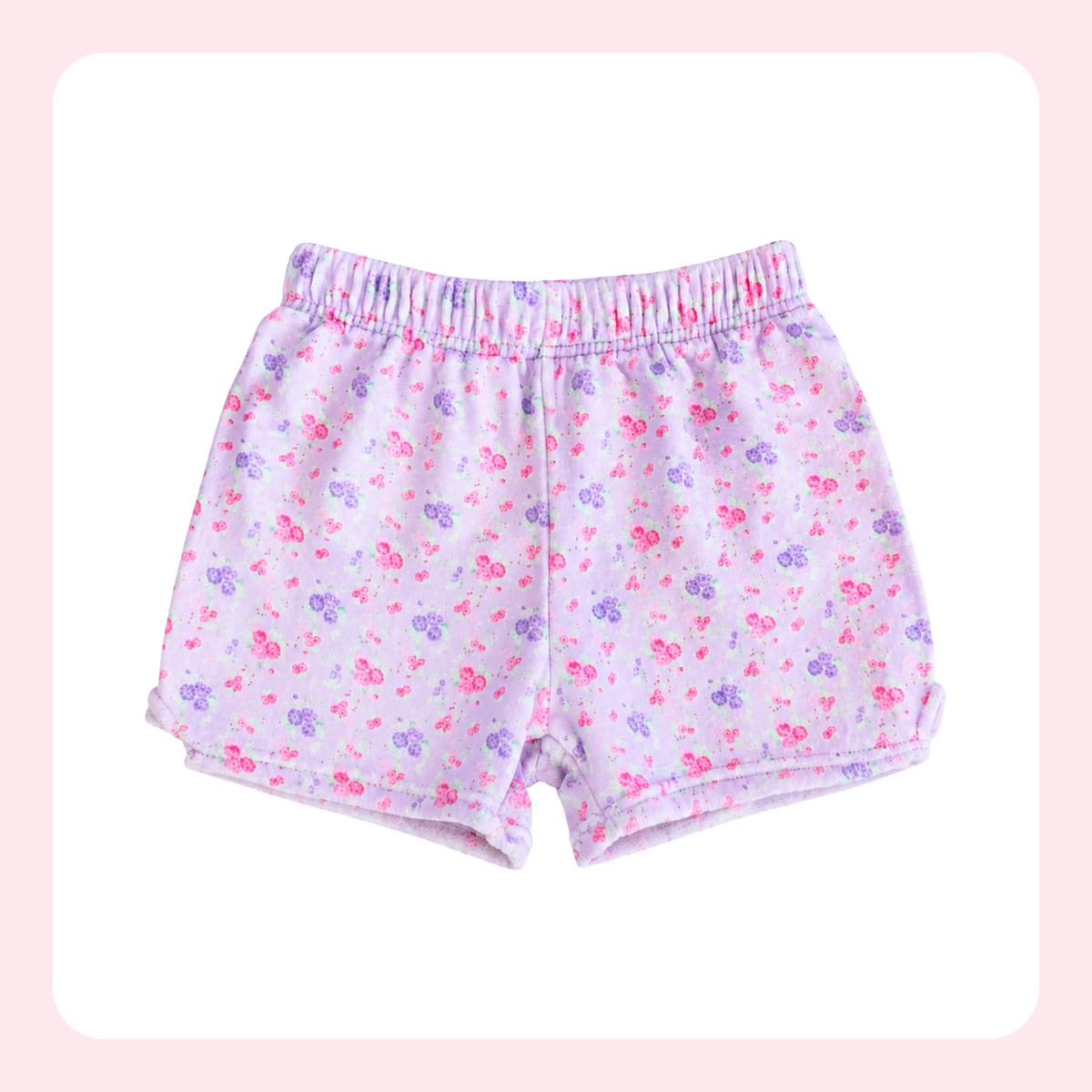 A pair of children's shorts with an elastic waistband, featuring a light pink and white base with a small pink and purple floral pattern, displayed on a white background with a soft pink border.