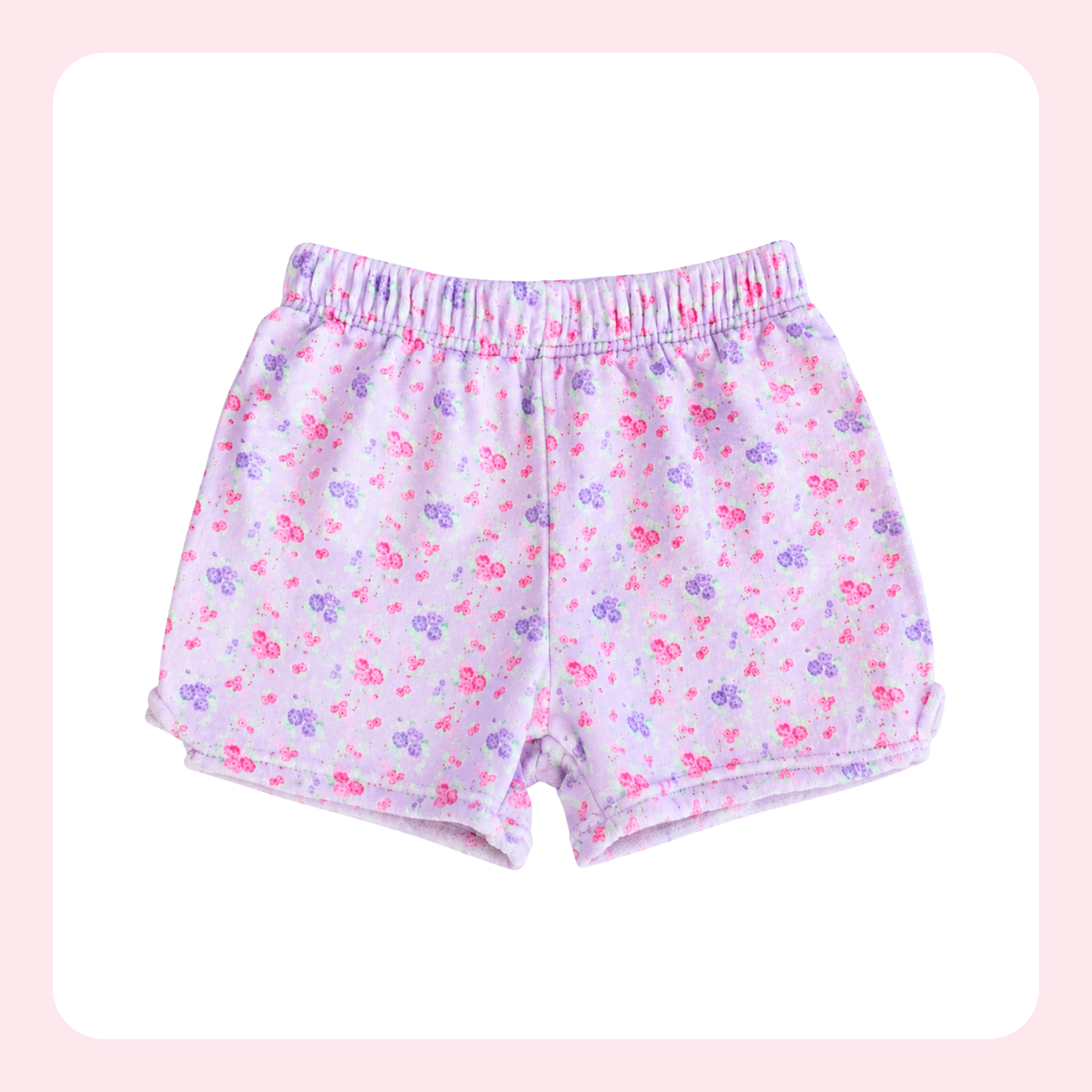 A pair of children's shorts with an elastic waistband, featuring a light pink and white base with a small pink and purple floral pattern, displayed on a white background with a soft pink border.