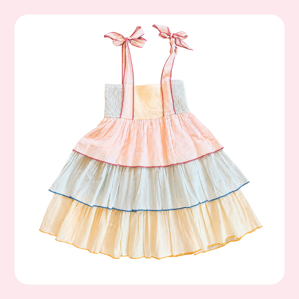 A pastel tiered babydoll dress with pink ribbon shoulder straps tied in bows, featuring layers of peach, pale blue, and cream ruffles with thin colored trim.
