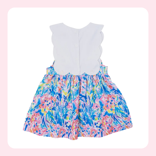 A sleeveless baby dress with a solid white scalloped back panel and a colorful floral watercolor print skirt in shades of blue, pink, yellow, and green, shown against a white background with a light pink border.